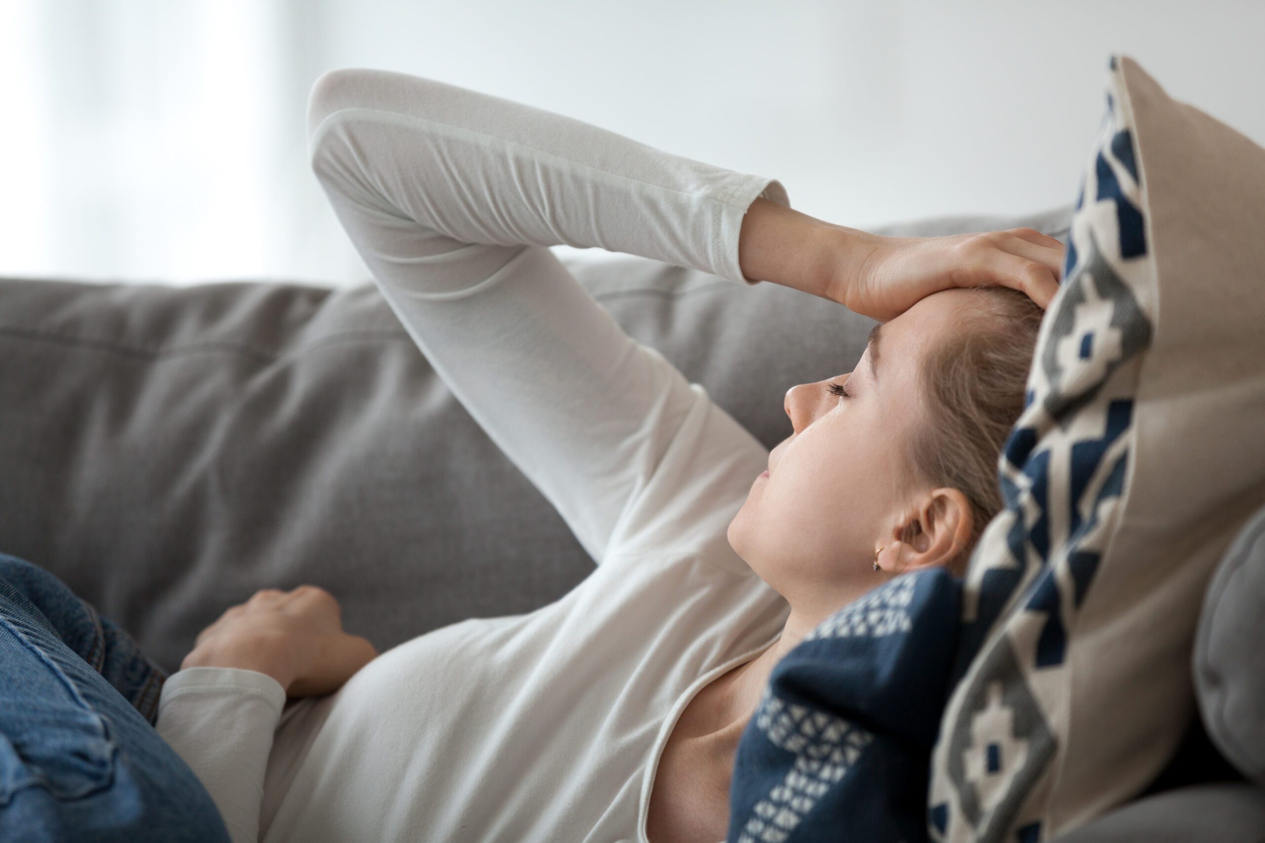 Woman lying on a sofa appearing distressed or exhausted